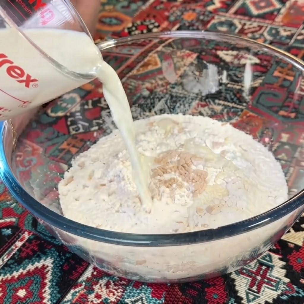 Milch wird aus einem Messbecher in eine Schüssel mit Mehl und Hefe gegossen.