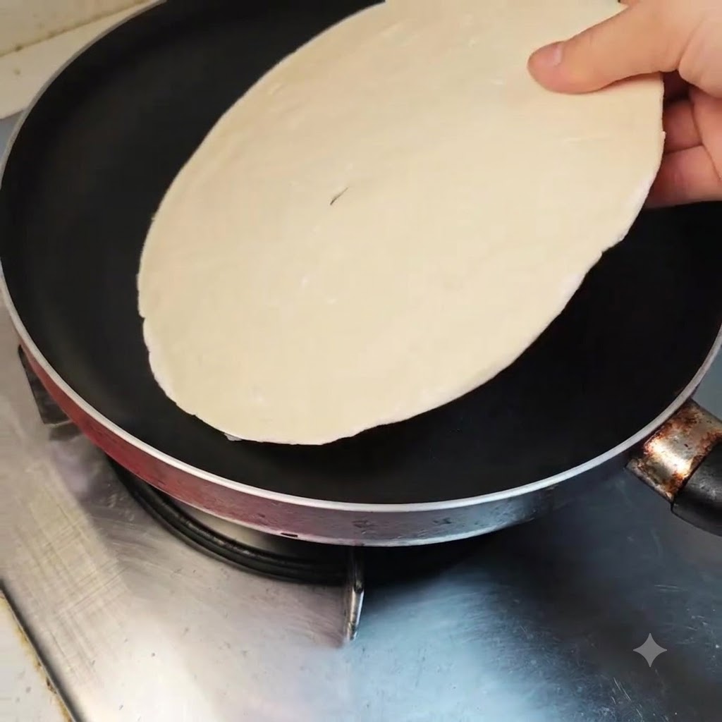 Ein Frühlingszwiebel-Pfannkuchen wird flach in eine saubere, kalte beschichtete Bratpfanne gelegt.