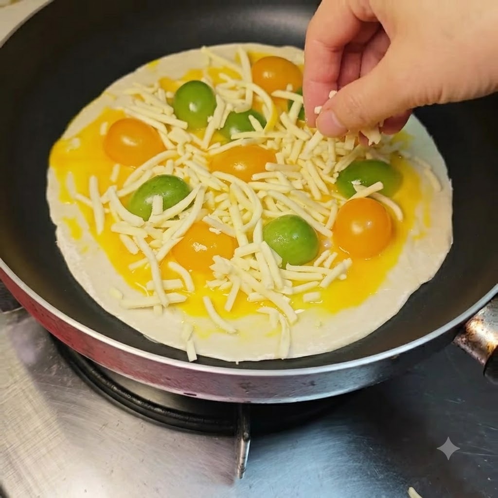 Geriebener Mozzarella wird von Hand über die Tomaten- und Eischicht gestreut.