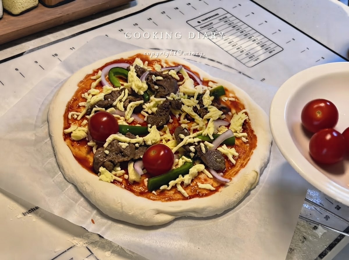 Eine vollständig belegte Pizza mit Käse, Rindfleisch, Paprika, Zwiebeln und ganzen Kirschtomaten auf Backpapier.