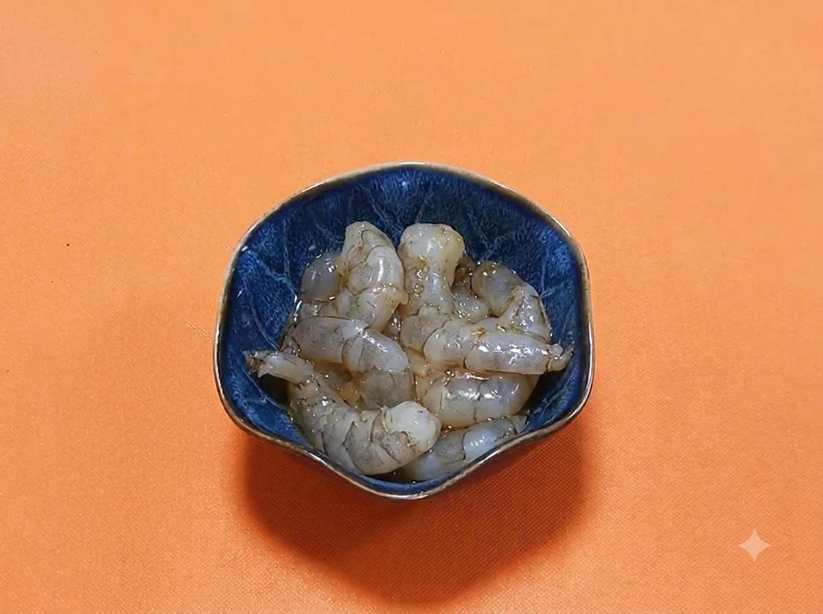 Geschälte rohe Garnelen in einer dunkelblauen Schüssel mit einer glänzenden Marinade aus dunkler Sojasauce und Gewürzen.