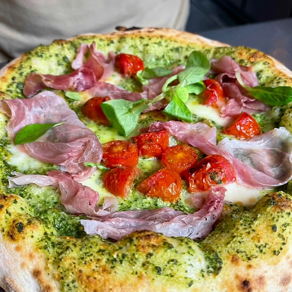 Frische grüne Kräuter und gehackte Walnüsse werden über die Oberseite einer Pizza gestreut.