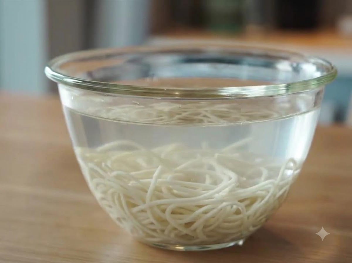 Frisch gekochte Ramen-Nudeln, die nach dem Abspülen in einer Glasschüssel mit kaltem Wasser schwimmen und abkühlen.