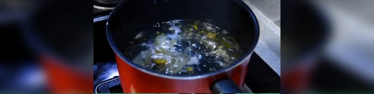 Ein dunkler Kochtopf mit Wasser, das auf dem Herd sprudelnd kocht.