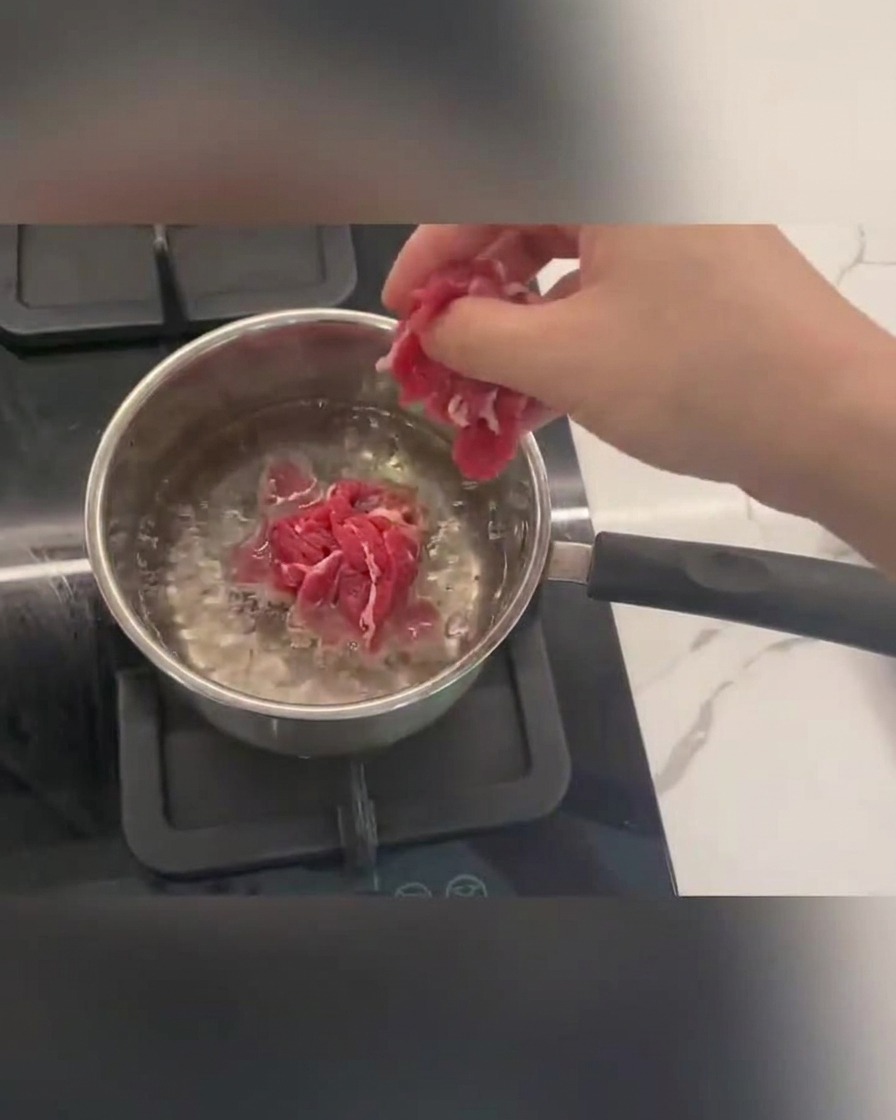 Rinderstreifen kochen in kochendem Wasser mit Schaum an der Oberfläche.