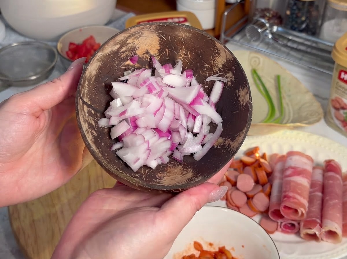 In kleine runde Scheiben geschnittene Würstchen auf einem Holzbrett neben gerolltem Fleisch angeordnet.