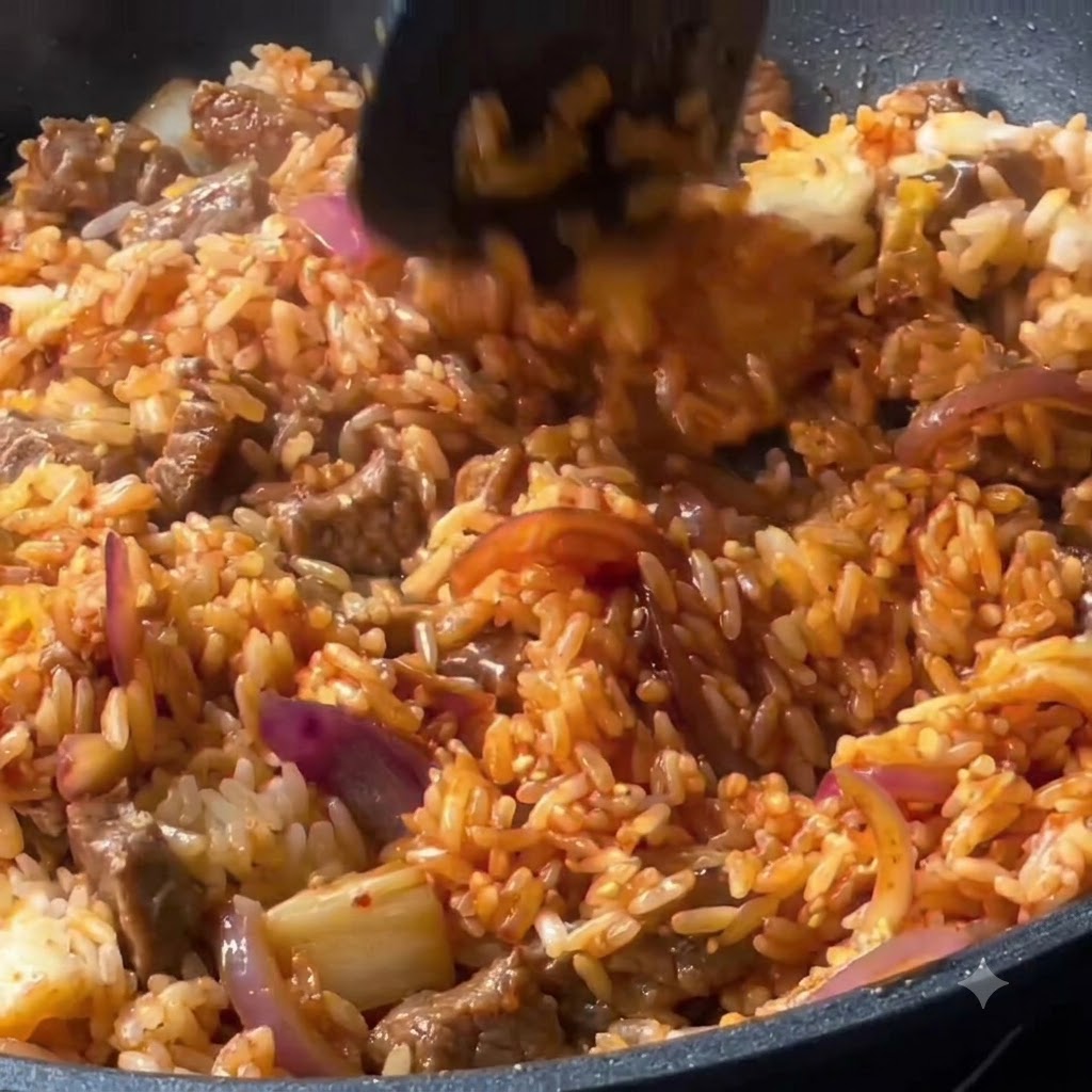 Reis, Rindfleisch und Gemüse werden in der Pfanne mit einem Pfannenwender gründlich vermischt.
