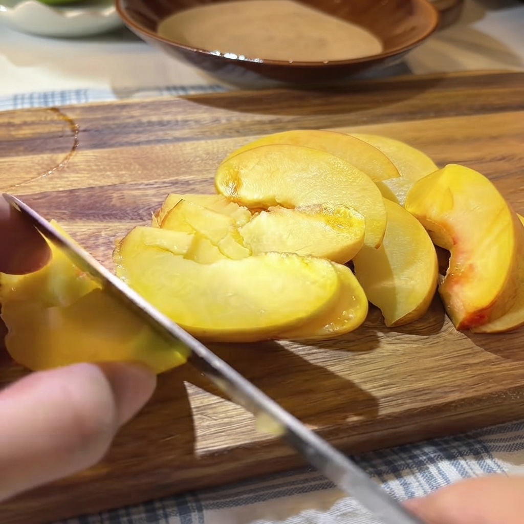 Frische Passionsfruchtkerne und Fruchtfleisch werden mit einem Löffel über die geschnittenen gelben Pfirsiche auf dem Schneidebrett gegeben.