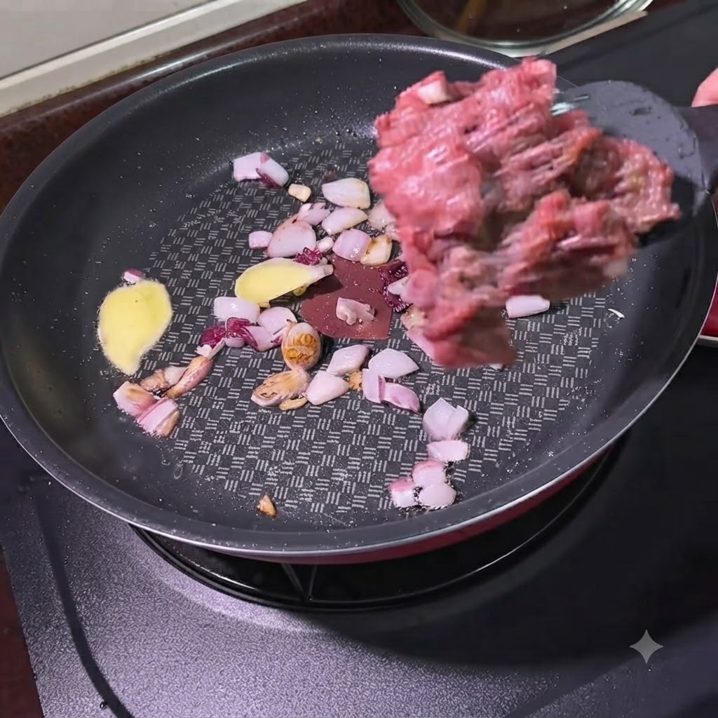 Rinderhackfleisch wird mit einem Pfannenwender in eine Pfanne mit sautierten Zwiebeln und Ingwerscheiben gegeben.