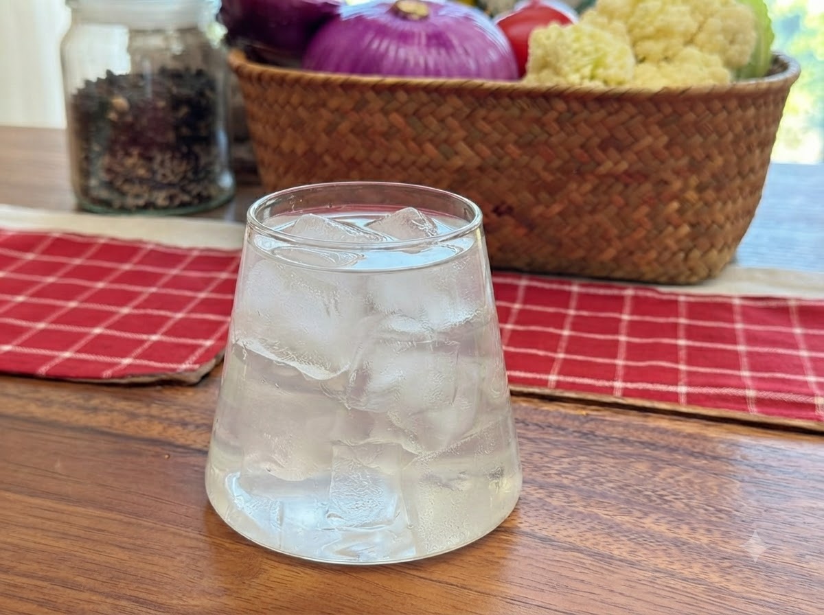 Kokoswasser wird in ein durchsichtiges Glas gefüllt, das mit Eiswürfeln gefüllt ist.