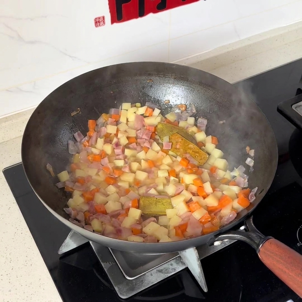 Gewürfelte Kartoffeln und Karotten werden in einem Wok mit Zwiebeln vermischt.