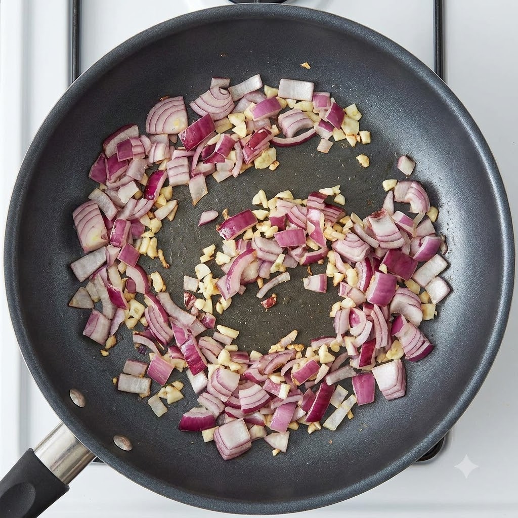 Currypastenblöcke in der Pfanne mit sautierten roten Zwiebeln und Knoblauch.