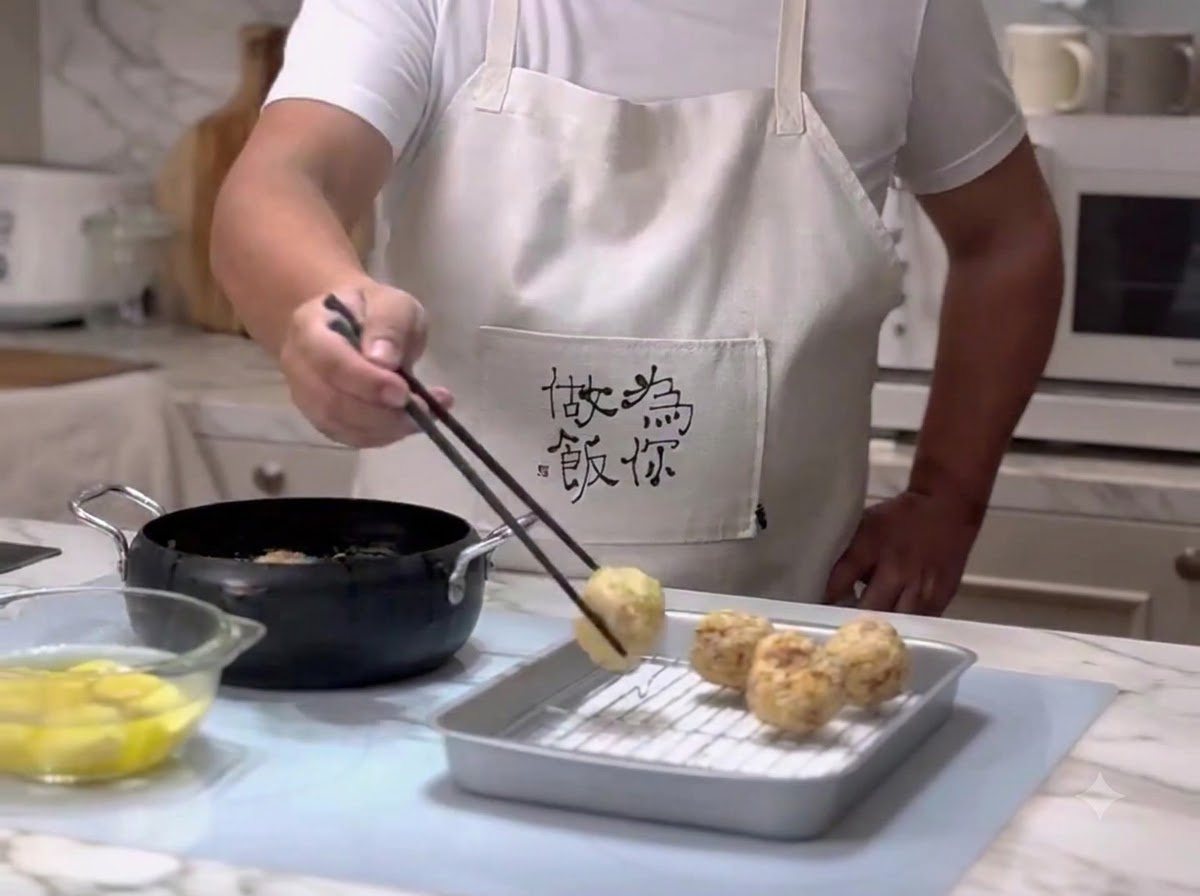 Fleischbällchen werden mit Stäbchen aus dem heißen Öl genommen und auf ein Abtropfgitter gelegt.