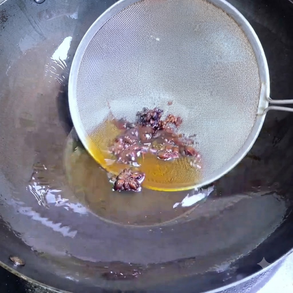 Ein Drahtsieb schöpft dunklen Sternanis und Sichuan-Pfefferkörner aus heißem Öl in einem Wok.