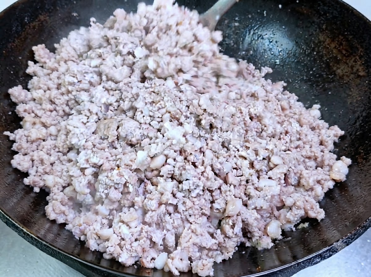 Schweinehackfleisch kocht und wird in einem eingearbeiteten Wok undurchsichtig.