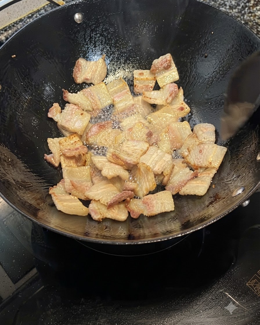 Schweinebauchscheiben braten in einem Wok, geben Fett frei und werden goldbraun.