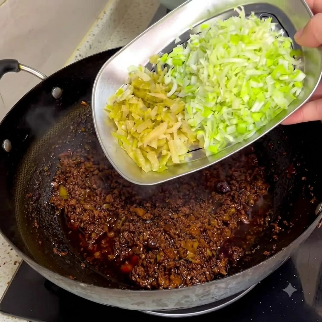 Gehacktes eingelegtes Senfgemüse und Frühlingszwiebeln werden von einem Metalltablett in eine dunkle Fleischsauce in einem Wok geschoben.