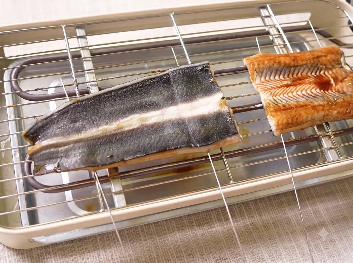 Aalfilets garen auf einem Elektrogrill mit Metallspießen, die durch das Fleisch stechen.