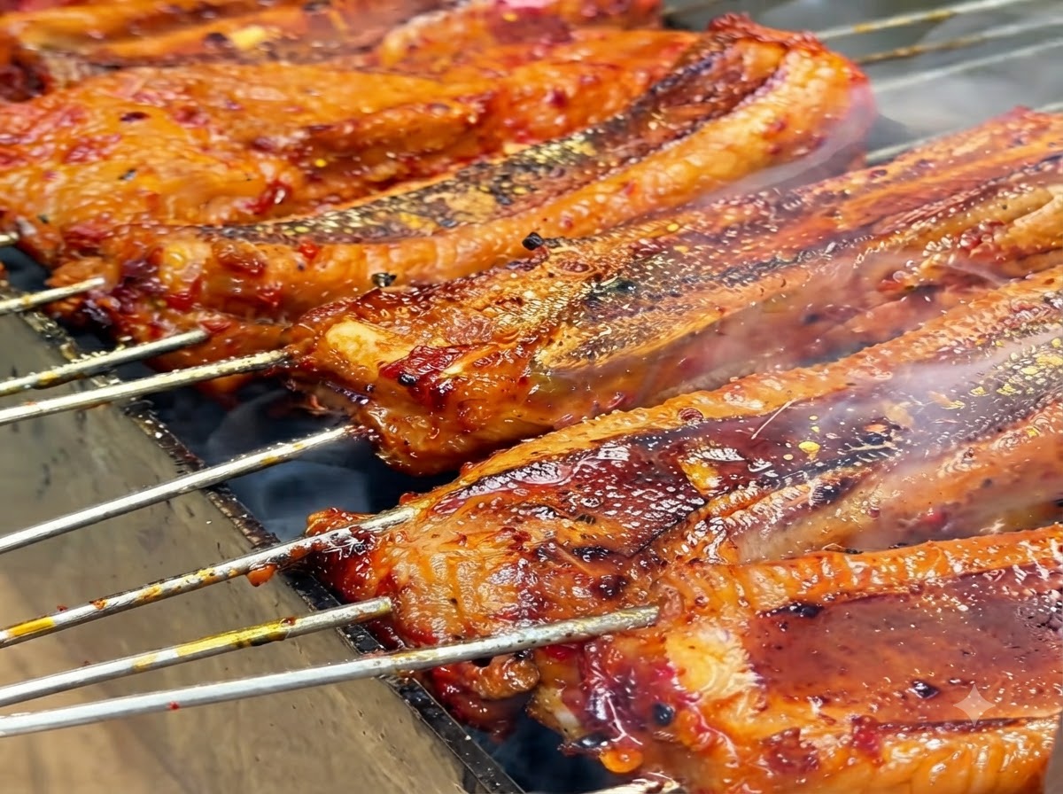 Gelbes Gewürzpulver wird auf grillende Rippchen gestreut.