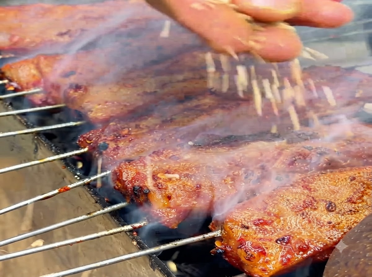 Weiße Sesamsamen fallen auf glänzende, gekochte Rippchen auf einem Grill.