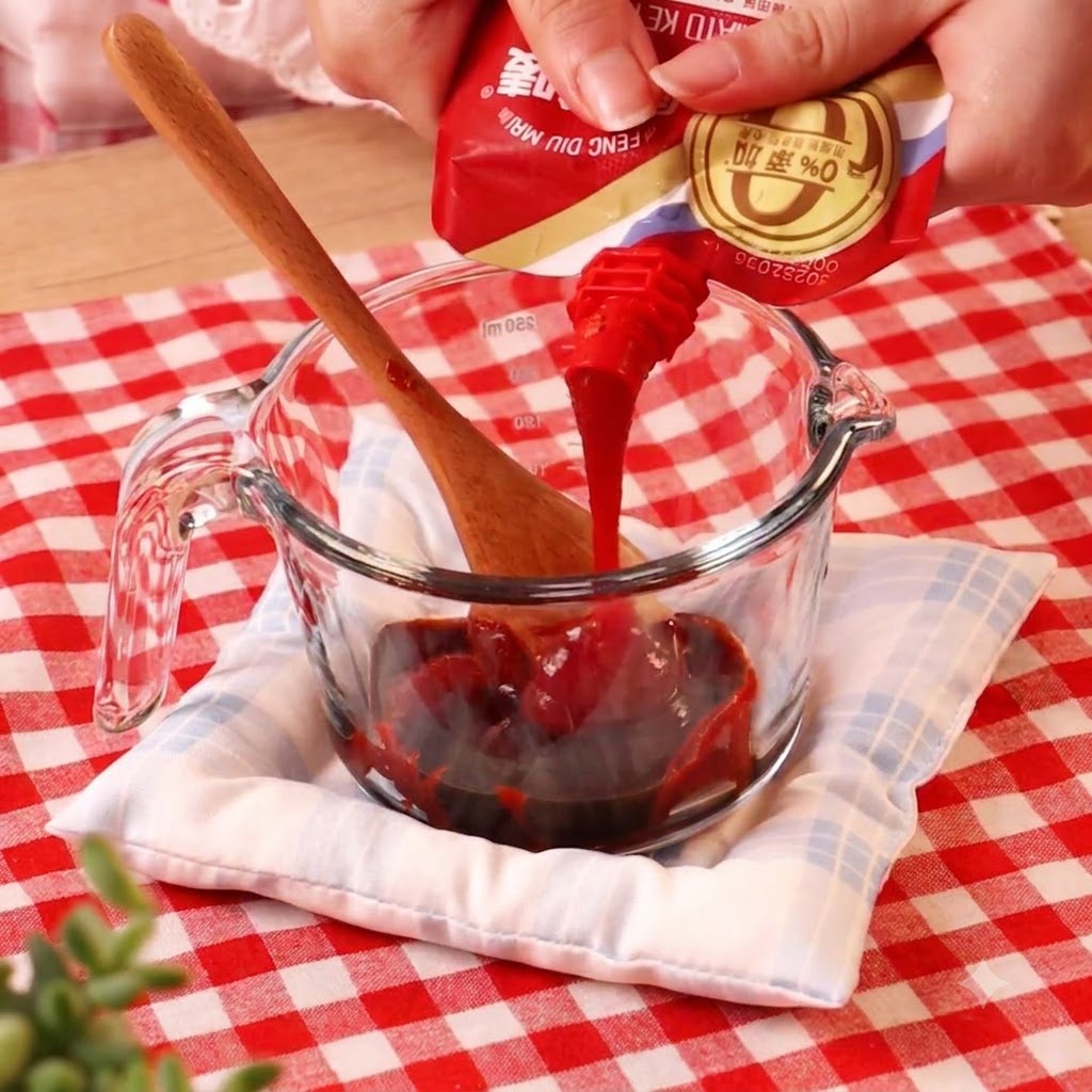 Chilipaste wird aus einer Packung in einen Glasmessbecher mit anderen Flüssigkeiten gegossen.