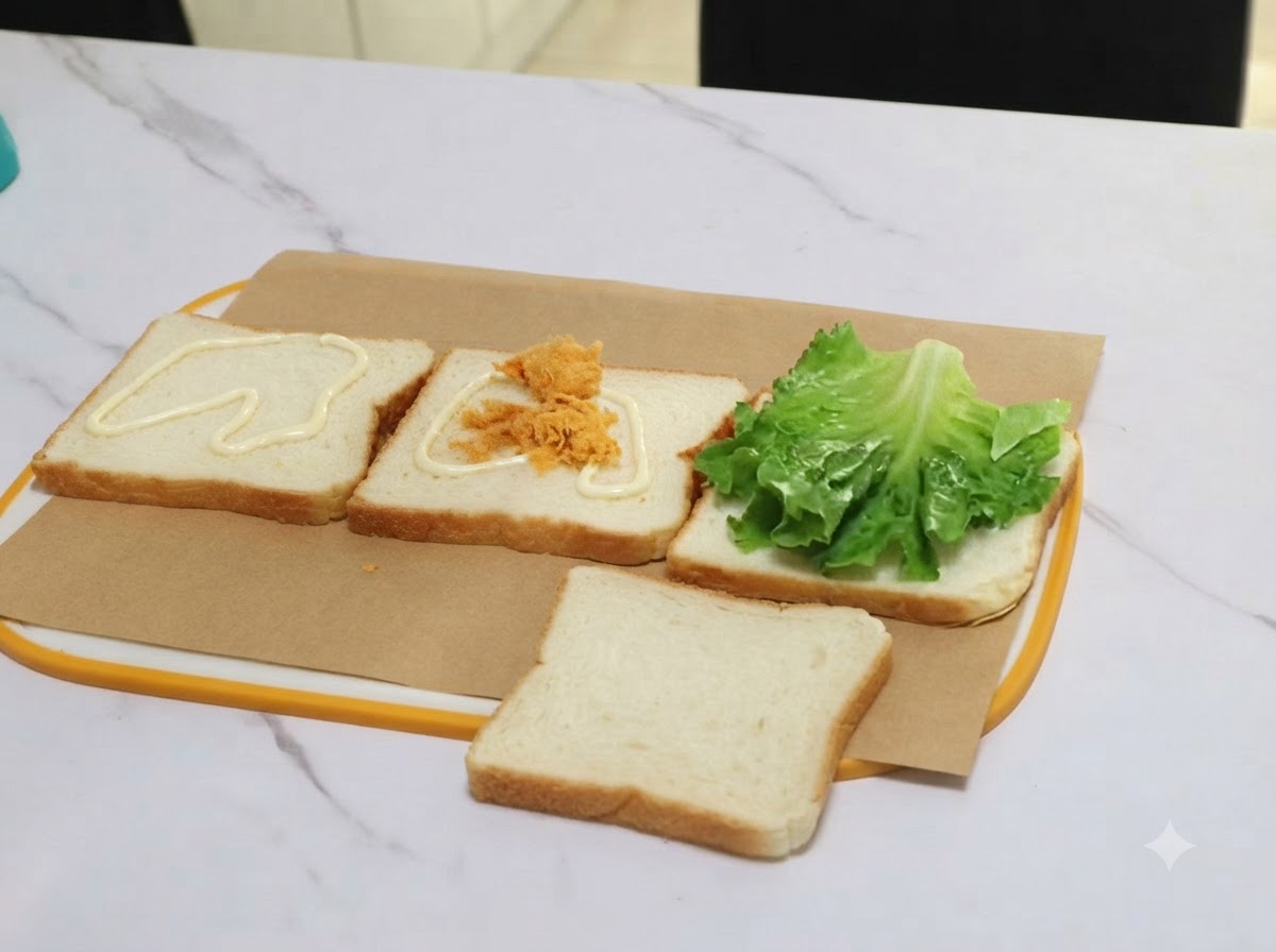 Eine Portion Fleisch-Floss wird mit einer Zange auf eine mit Sauce bestrichene Scheibe Brot gelegt.