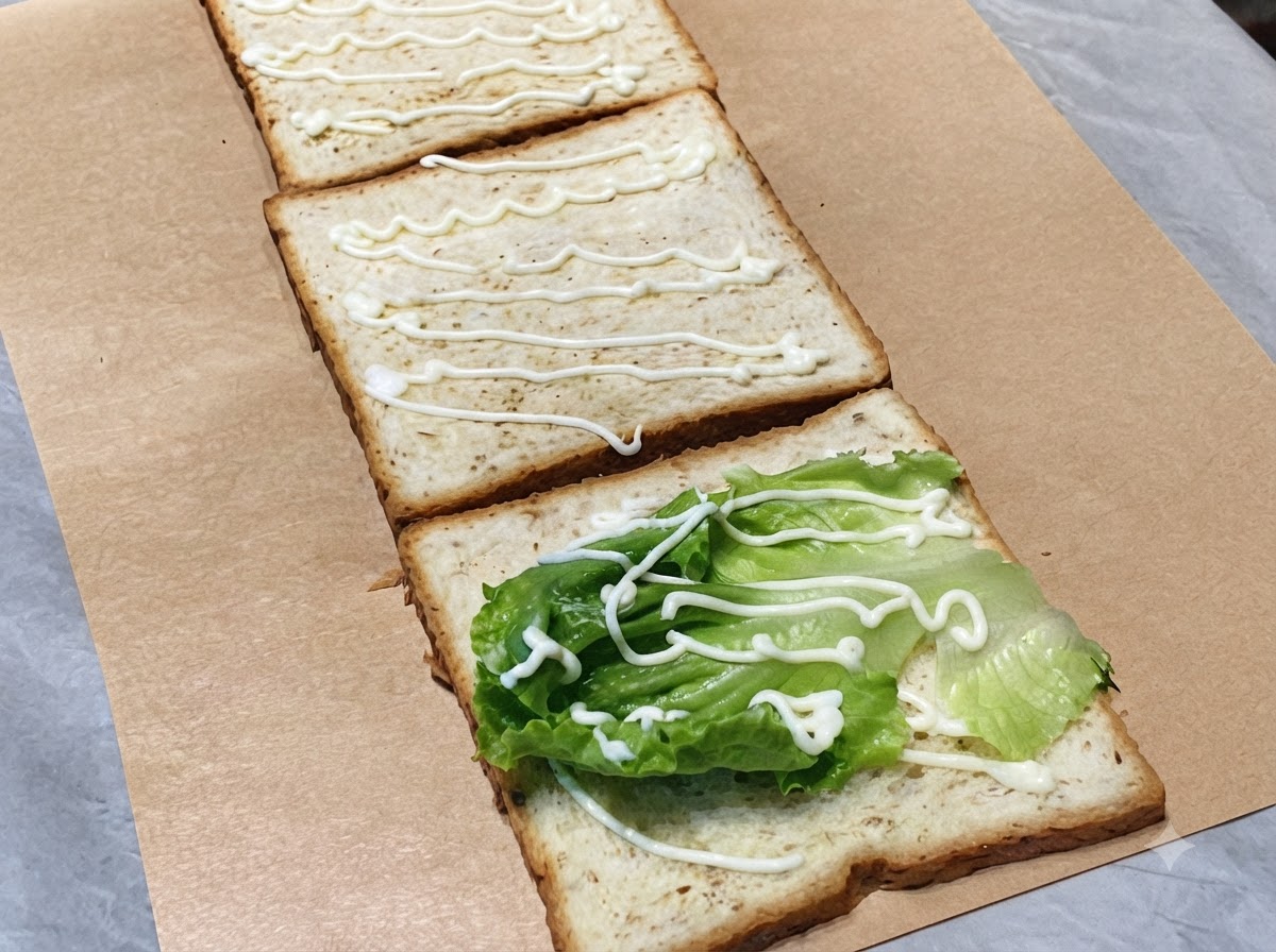 Frische Gurkenscheiben auf der zweiten Toastscheibe mit Mayonnaise.