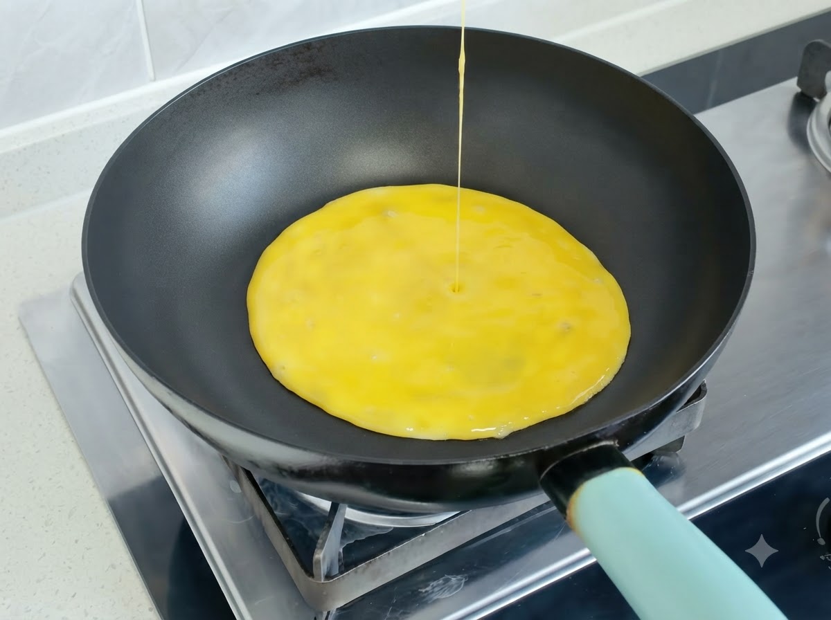 Verquirlte Eimischung wird in eine heiße Bratpfanne gegossen, um ein Omelett zu bilden.
