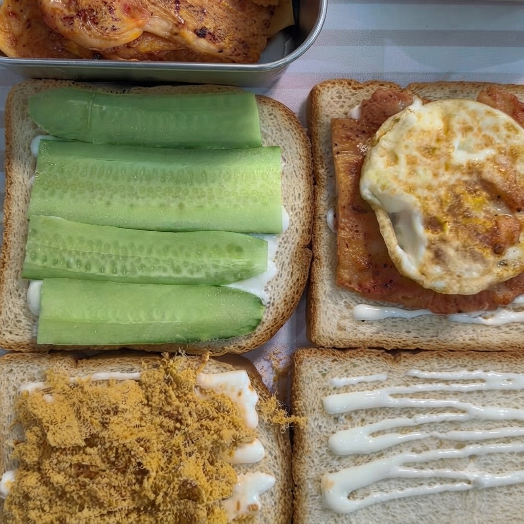 Eine Scheibe Sandwichbrot mit weißem Aufstrich, gekrönt von einem gekochten Stück gewürztem Hähnchen und einem Spiegelei.