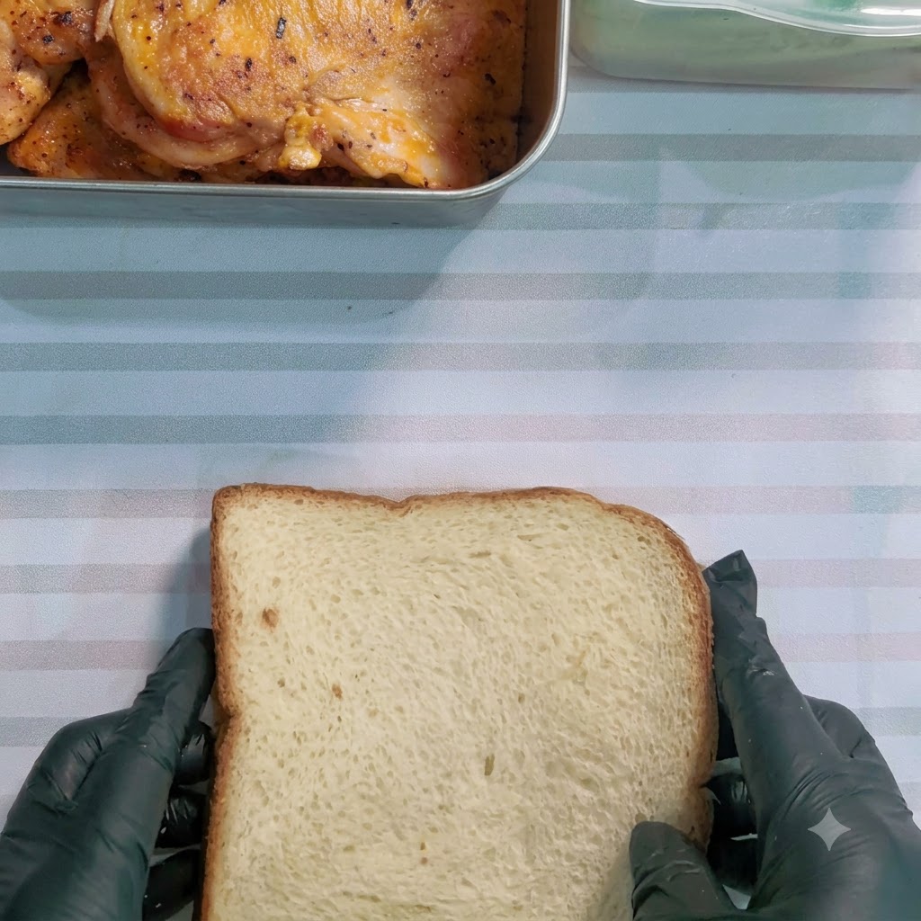 Ein Sägemesser schneidet diagonal durch ein eingewickeltes Sandwich auf einer gestreiften Oberfläche.