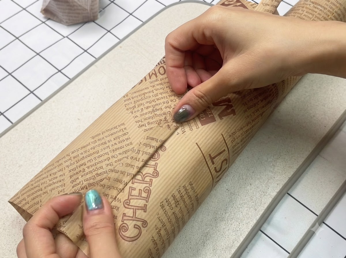 Ein frisch zubereitetes Sandwich wird fest und sicher in dekoratives braunes Backpapier eingewickelt.