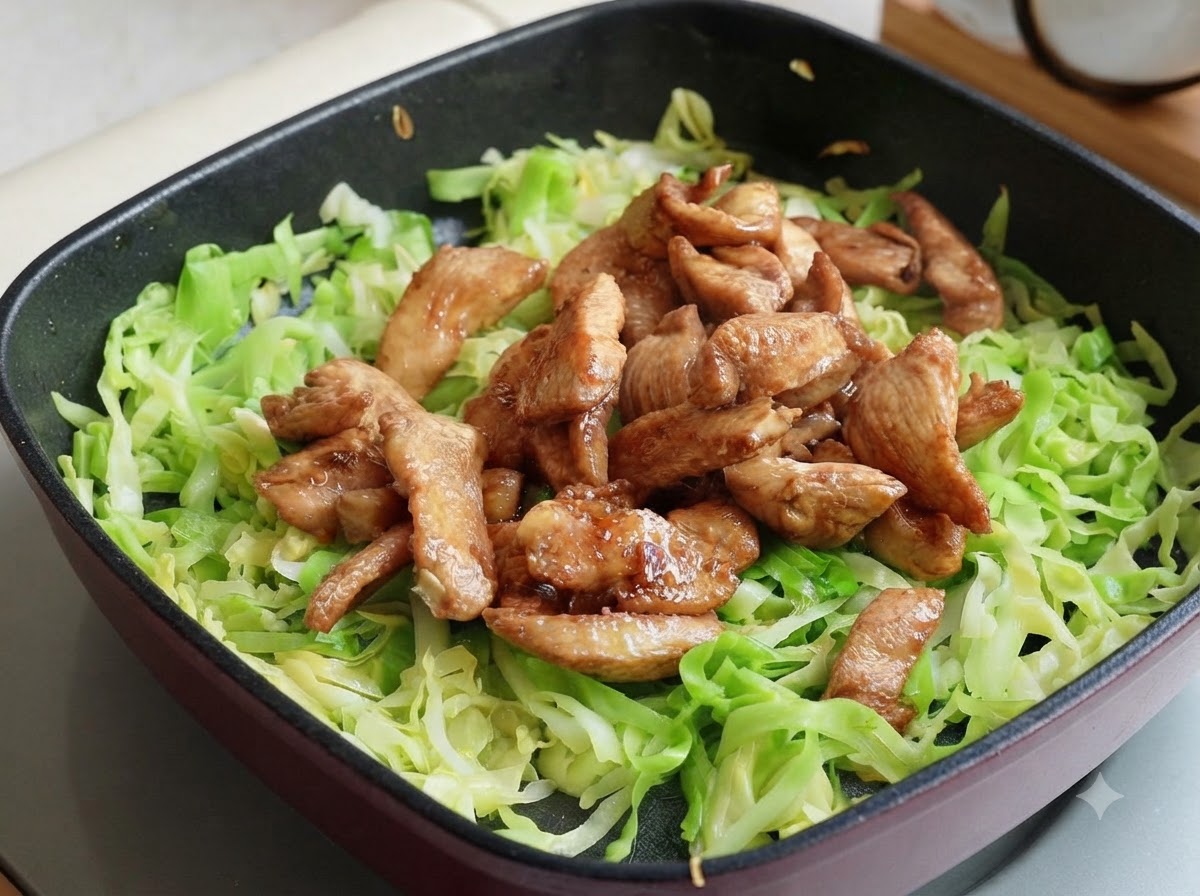 Gegarte Hähnchenbruststreifen liegen auf dem Kohl in der Pfanne, aufgeteilt in zwei Portionen.