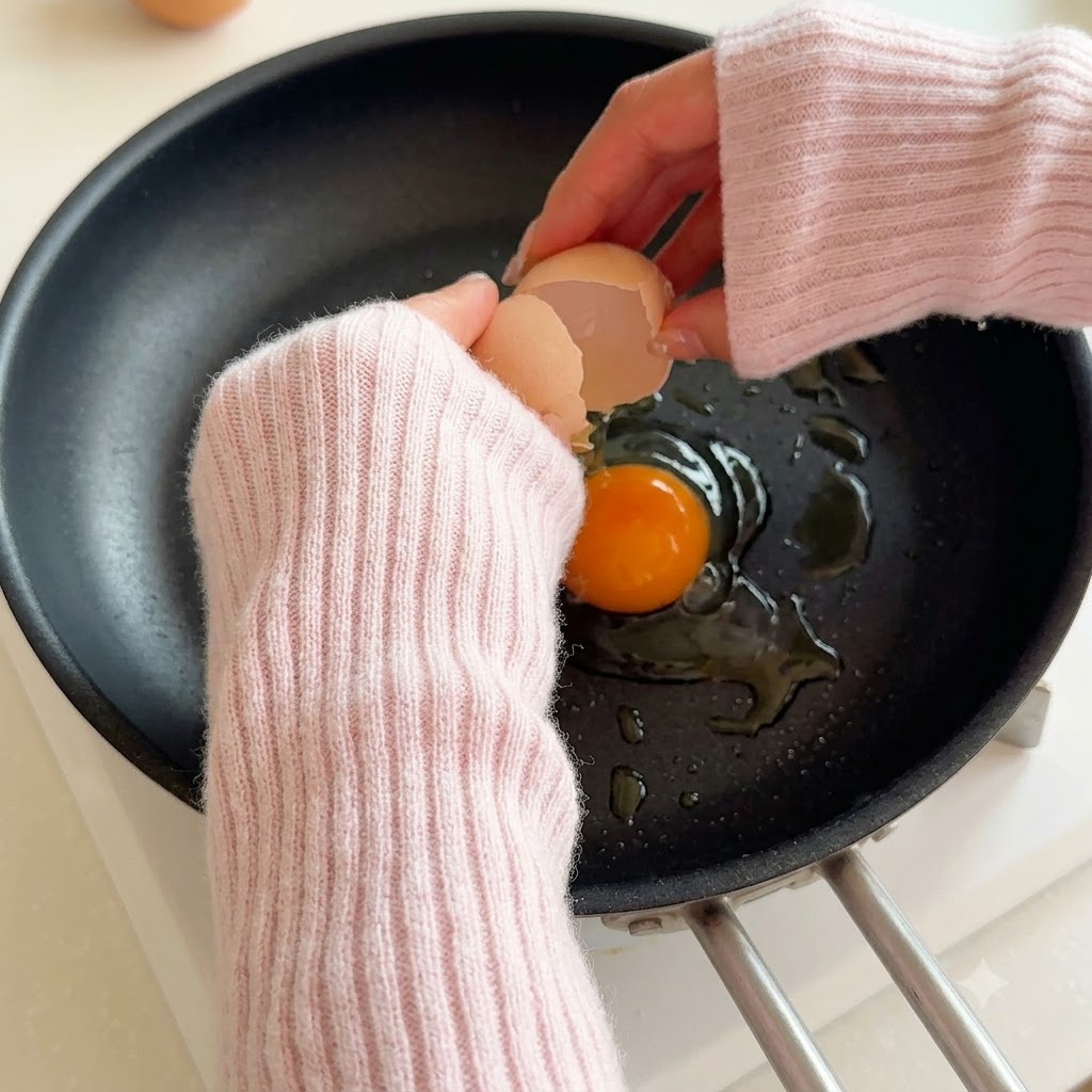 Ein Ei schlägt in eine heiße Pfanne mit Öl ein.