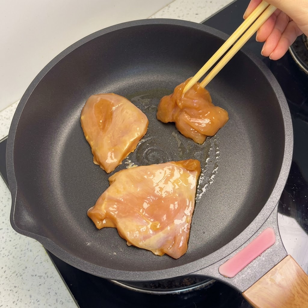 Goldbraune Hähnchenbruststücke garen in einer Pfanne.