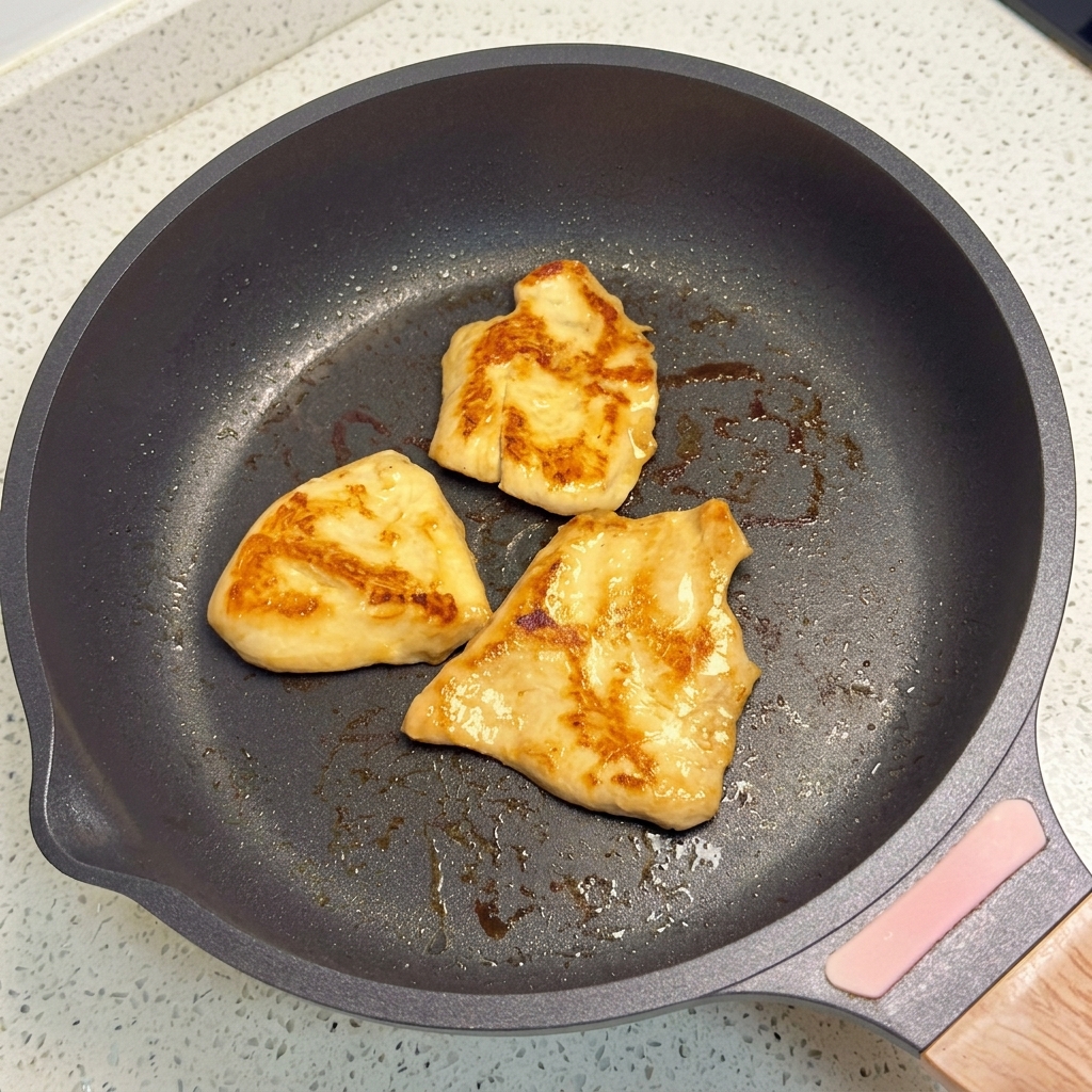 Hähnchenstücke braten in einer Pfanne mit flachem Boden, bis sie goldbraun sind.