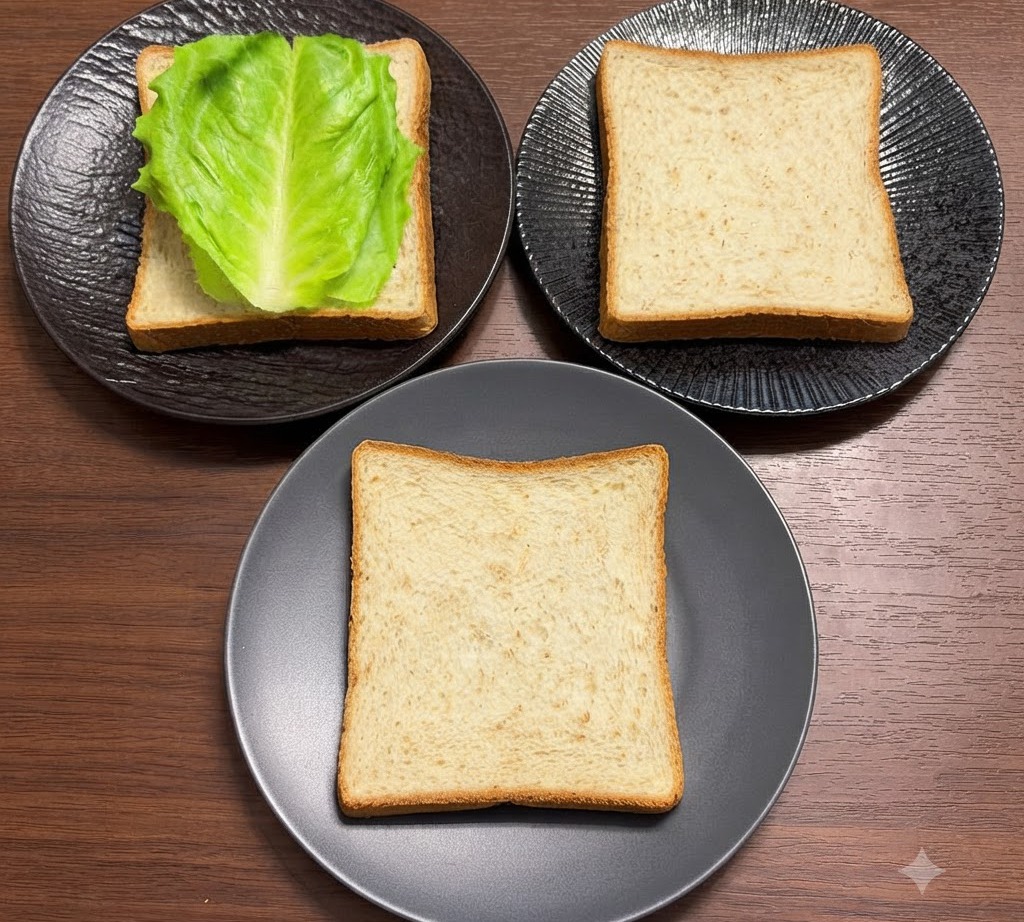 Frische grüne Salatblätter ordentlich auf Vollkornbrotscheiben angeordnet, die auf schwarzen Tellern liegen.