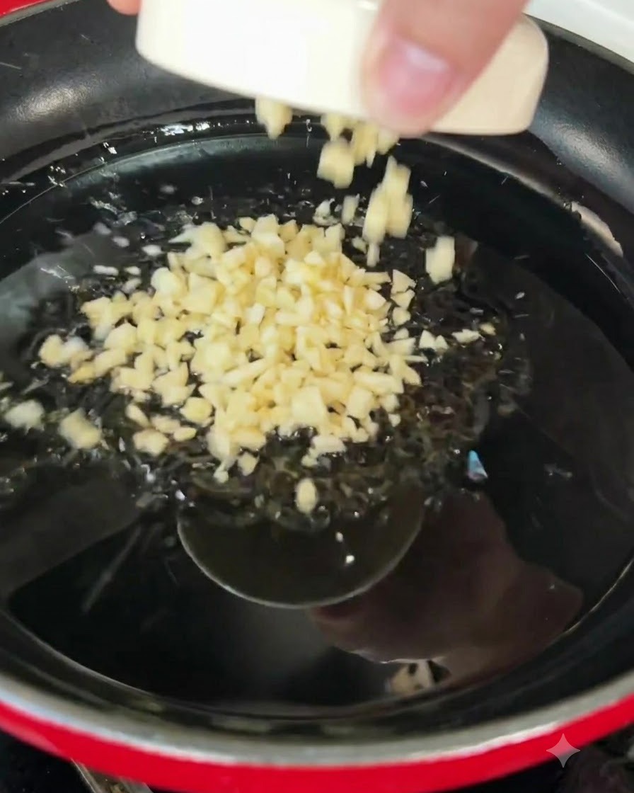 Gehackter Knoblauch brutzelt in heißen Olivenöl in einer Pfanne.