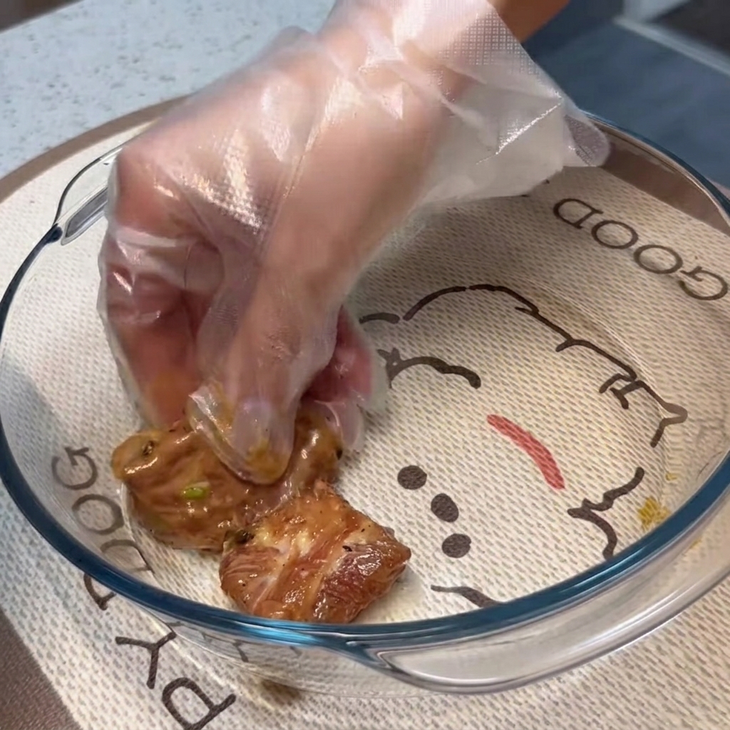 Marinierte Schweinerippchen werden flach und in einer einzigen Schicht in einer klaren Glasauflaufform ausgelegt.