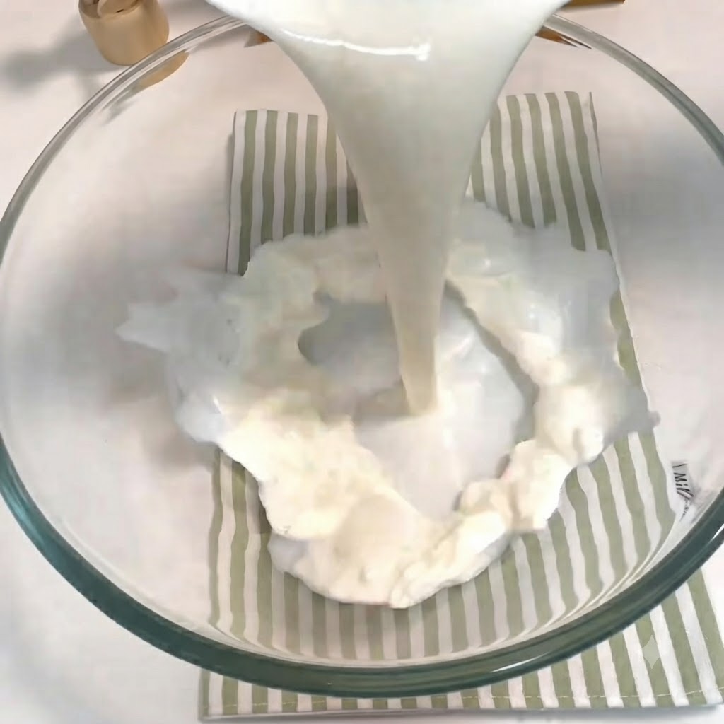 Milch, Zucker, Hefe und ein Ei werden in einer Glassschüssel zusammengegossen und verquirlt.