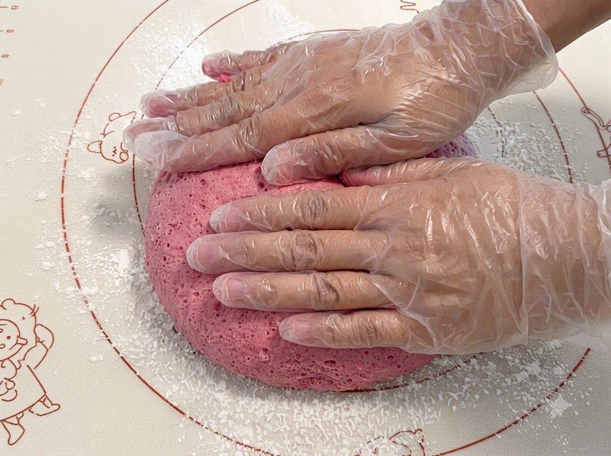 Fermentierter rosa Teig wird auf einer Silikonmatte gedrückt und geknetet.