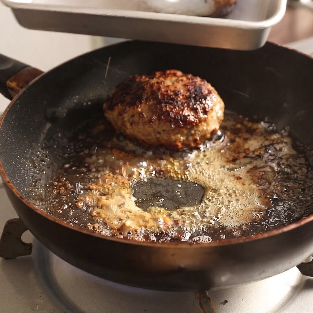 Hamburger-Patties werden mit einer Metallzange aus einer heißen Pfanne gehoben.