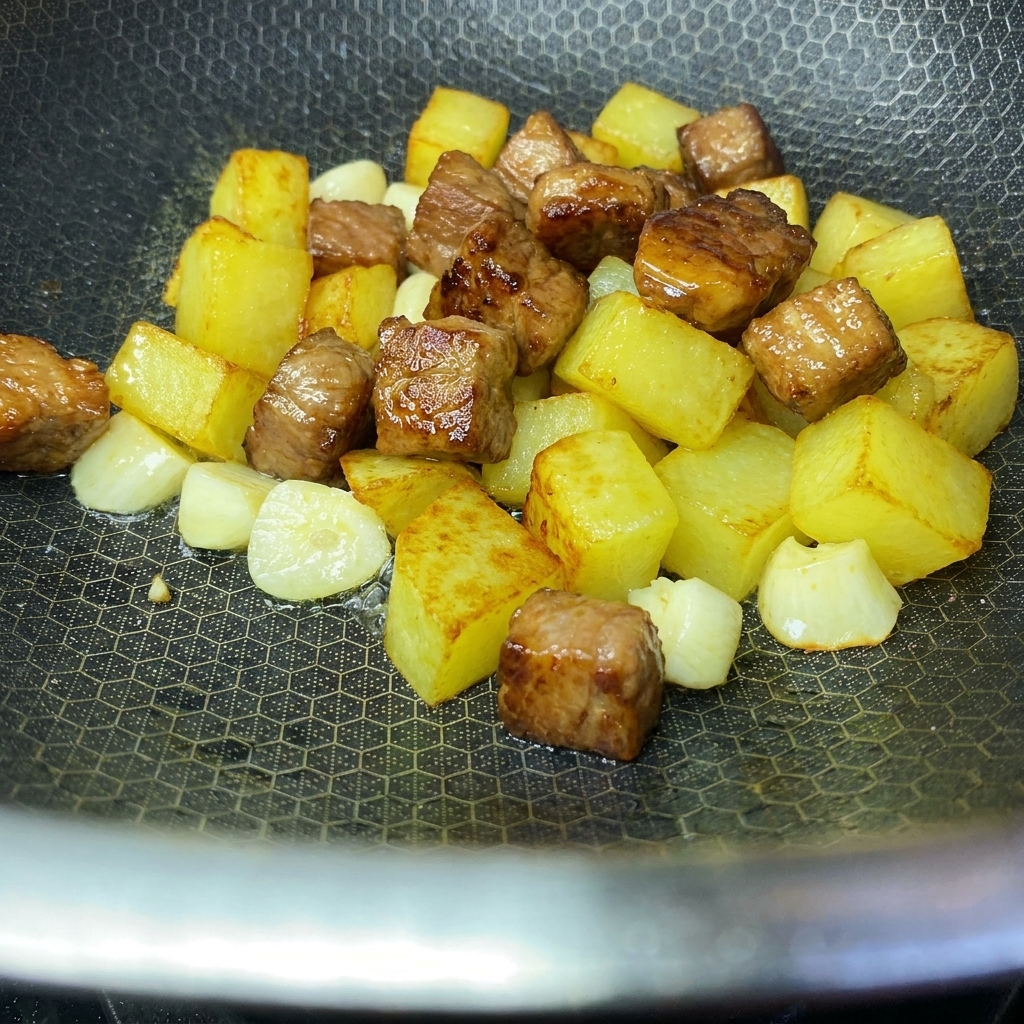 Goldbraune, knusprige Kartoffelwürfel und angebratene Schweinefleischwürfel vereinen sich in einem Wok.