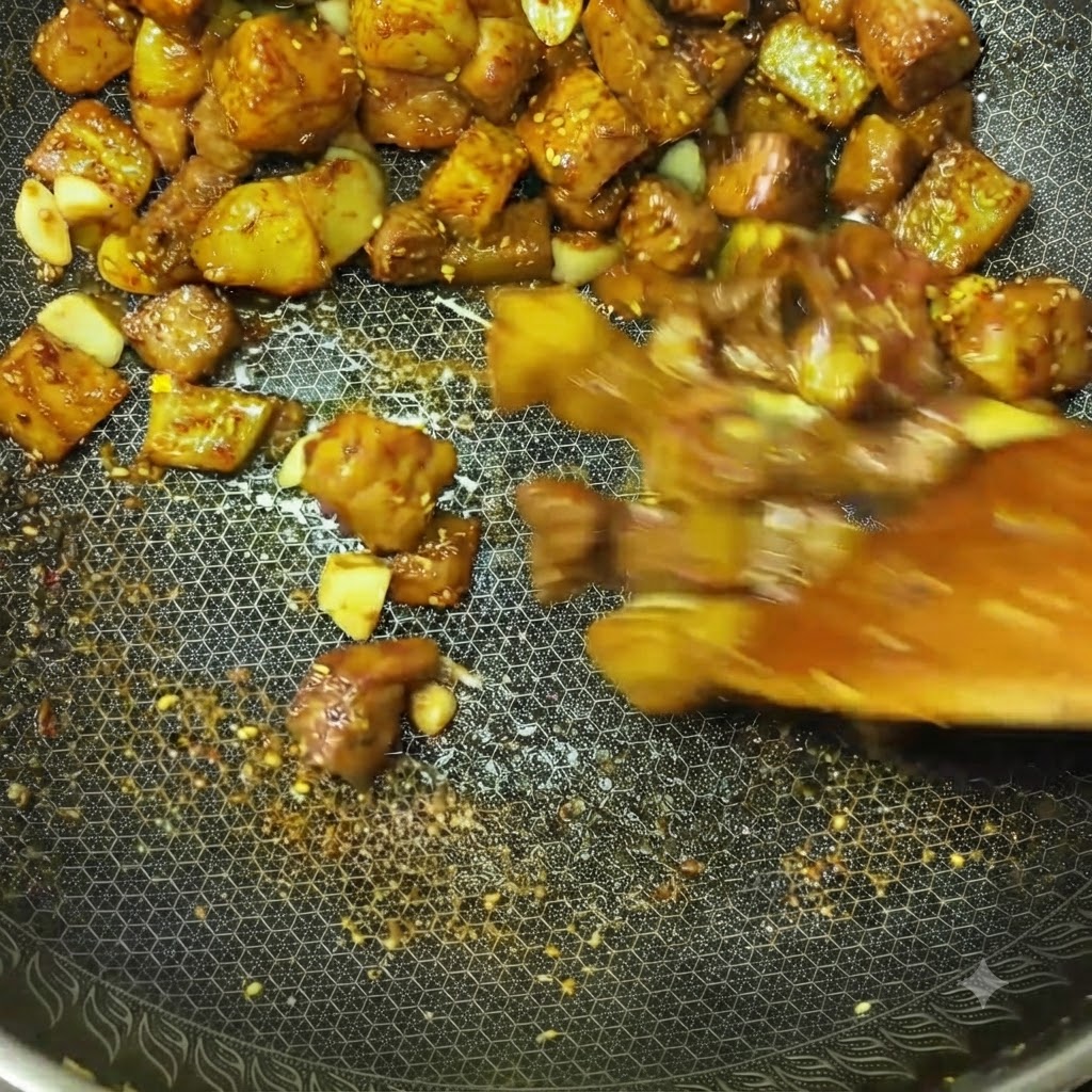 Fleischwürfel und Kartoffelstücke werden in einem Wok rasant mit sichtbaren Gewürzen und Aromen pfannengerührt.