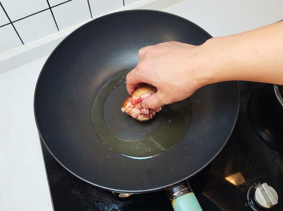 Ein gefüllter Pilz wird mit der Fleischseite nach unten in einen heißen, geölten Wok gelegt.