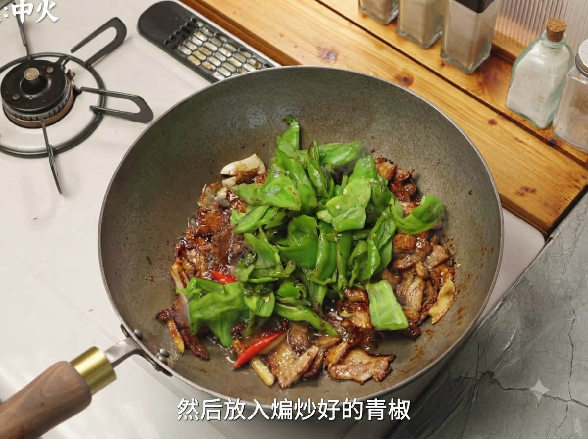 Grüne Paprika und Pilze werden zum gewürzten Schweinefleisch in den Wok gegeben.