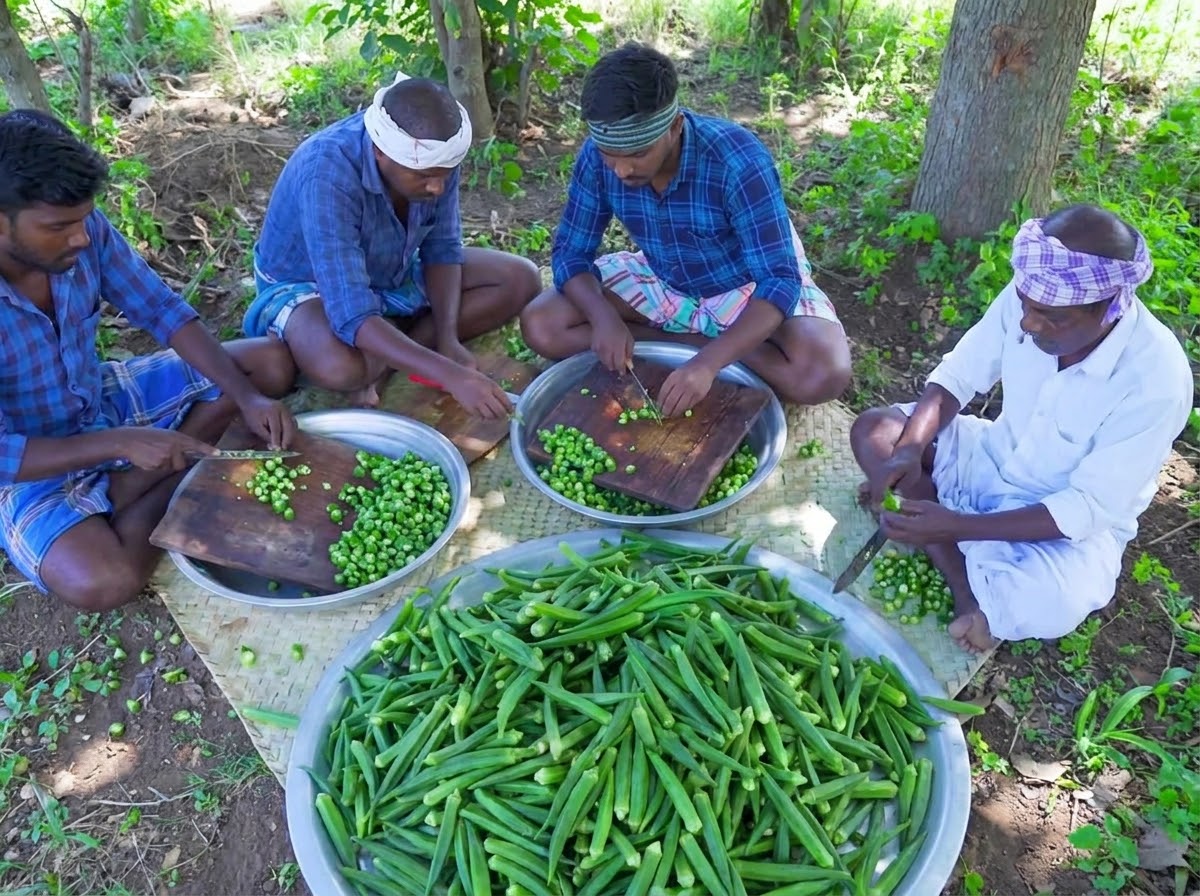 Mehrere Personen sitzen und hacken rohe grüne Okra auf Holzschneidebrettern.