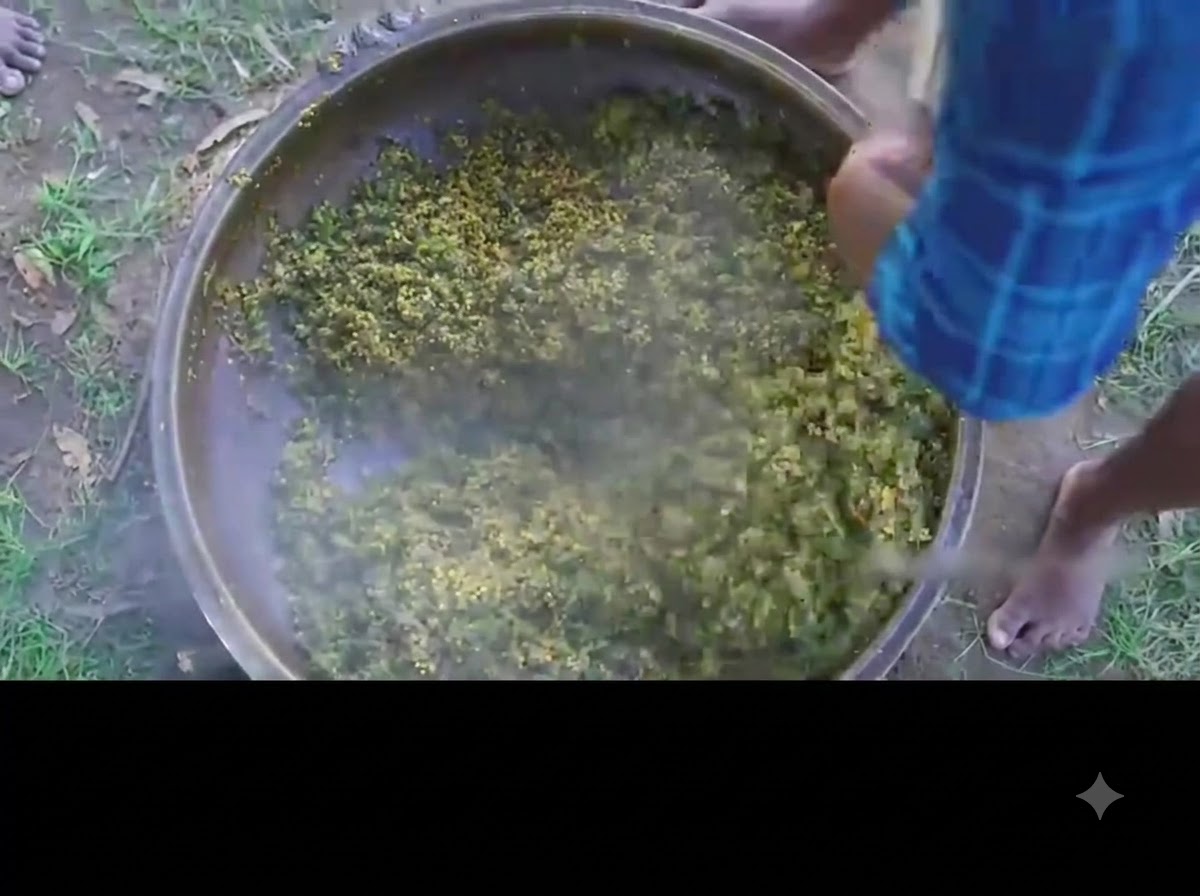 Eine Person rührt das fertige grüne Okra-Eier-Curry in einem großen Eisernen Topf um.