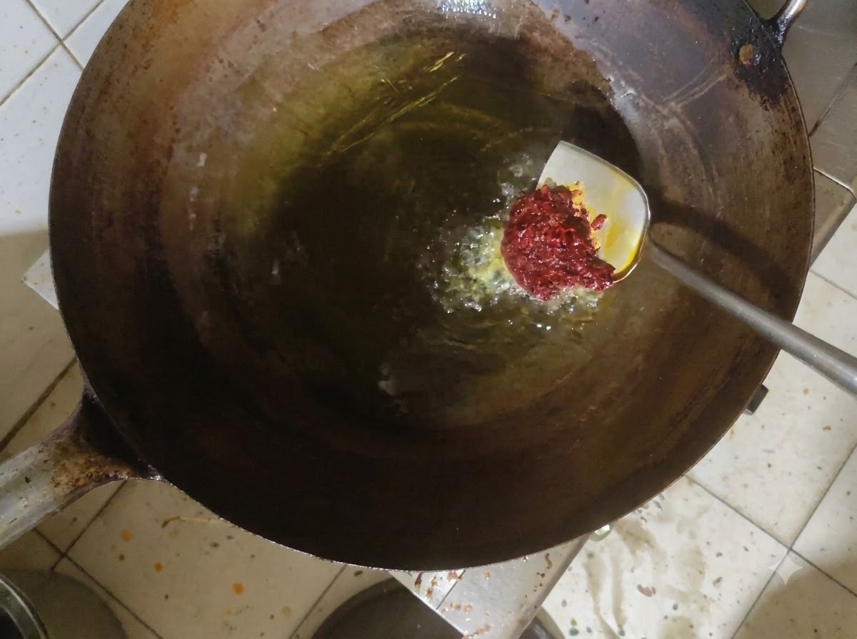 Doubanjiang-Paste wird in heißem Öl in einem Wok verrührt.
