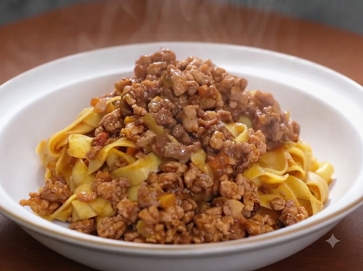 Tomatenmark wird in einer Pfanne unter eine gebräunte Fleisch-Gemüse-Mischung gehoben.