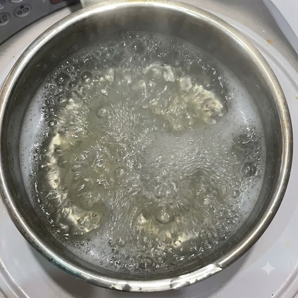 Olivenöl wird in einen Topf mit kochendem Wasser und Penne-Nudeln gegossen.